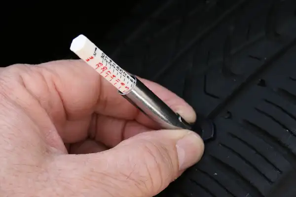 Using a tread-depth gauge to measure a car tyre