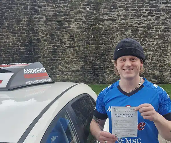 Jac by the castle walls in Conwy, showing off his new pass certificate