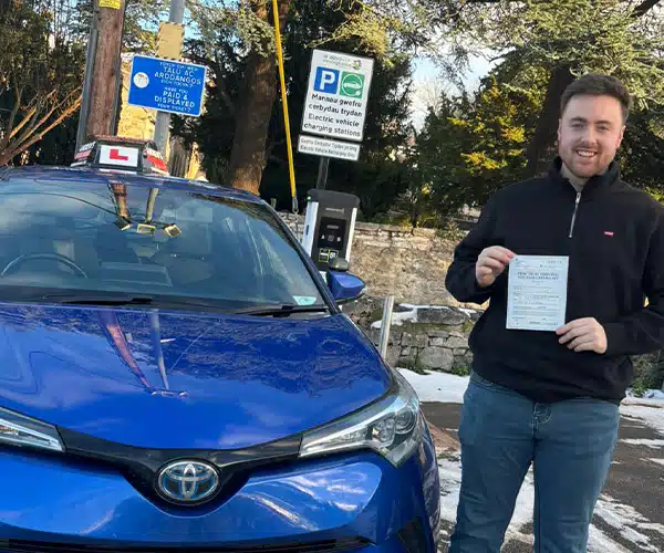 Jake in a car park with his driving instructors car