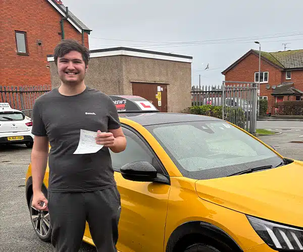 James with a Yellow car and pass certificate in the Rhyl Driving Test Centre