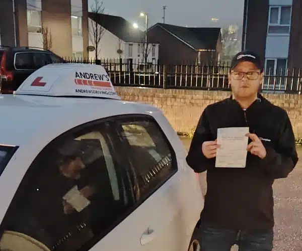Karl in Colwyn Bay holding his pass certificate after a late driving test just before dusk