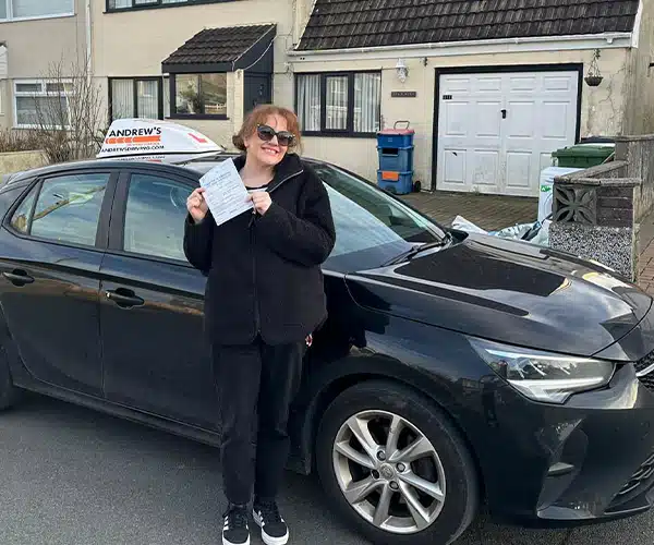 Kiera in Holyhead with her new pass certificate, standing next to her instructor geraints car
