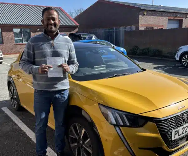 Harry in The Rhyl Driving Test Centre with his pass certificate and Paul Crafts car