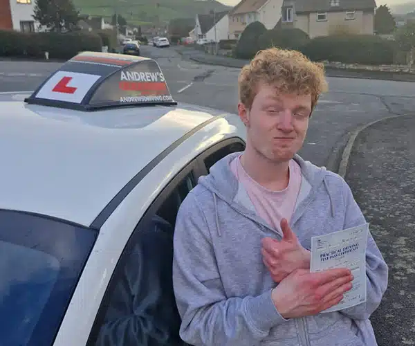 Isaac in Colwyn Bay with his pass certificate and Paul Sanders Tuition car