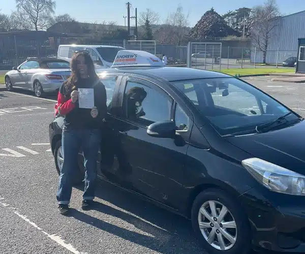 "Isla with her driving test certificate, with Shane's car in Bangor Driving Test Centre car park"