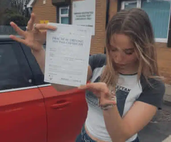 Jess holding her pass certificate after her driving test at Upton Driving Test Centre
