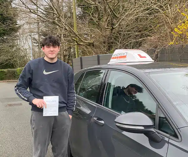 Luke from Mold holding his pass certificate besideter successfully passing his driving test in Rhyl