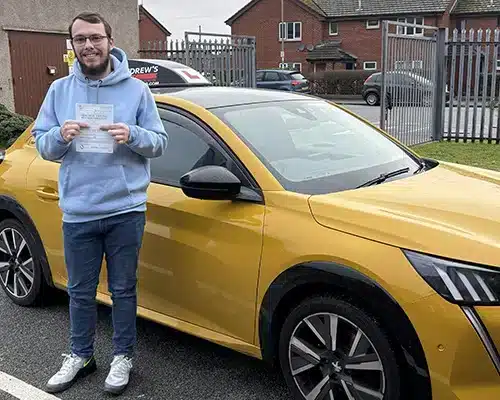 Ben Carter holding his driving test pass certificaw driving school car at Rhyl Driving Test Centre.