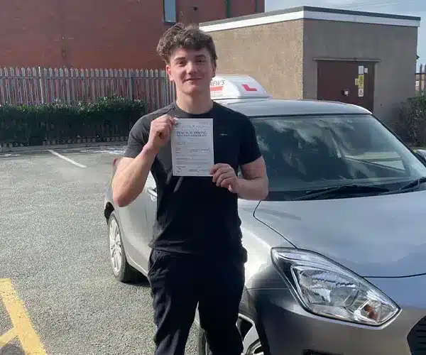 Rhys holds his driving test pass certificate while beside Llinos’s car at Rhyl Driving Test Centre.