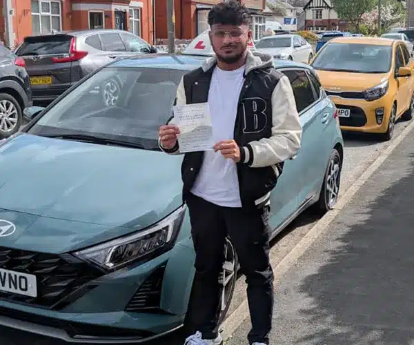 Ahsan in Colwyn Bay standing next to Jacks tuition car with his driving test pass certificate