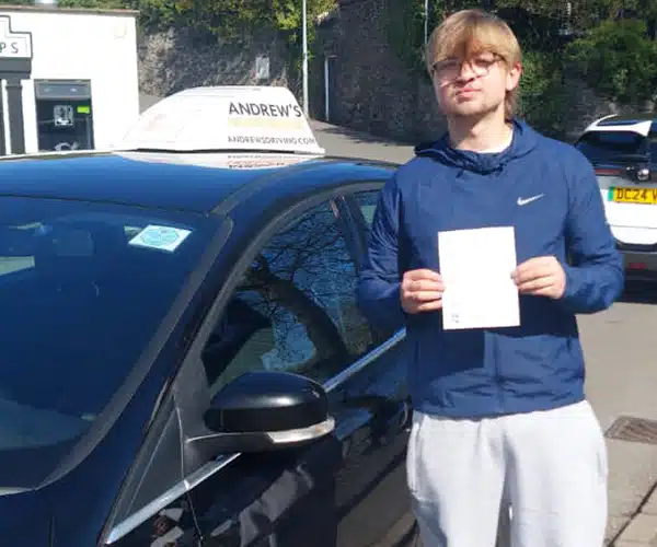 "Alfie in Colwyn Bay holding his driving test pass certificate by an Andrew's Driving Car"