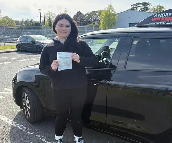 Arffena holding driving test pass certificate at Bangor Driving Test Centre with instructor car
