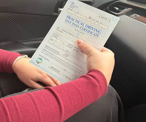Chelsea holding practical driving test pass certificate inside car after passing in Rhyl