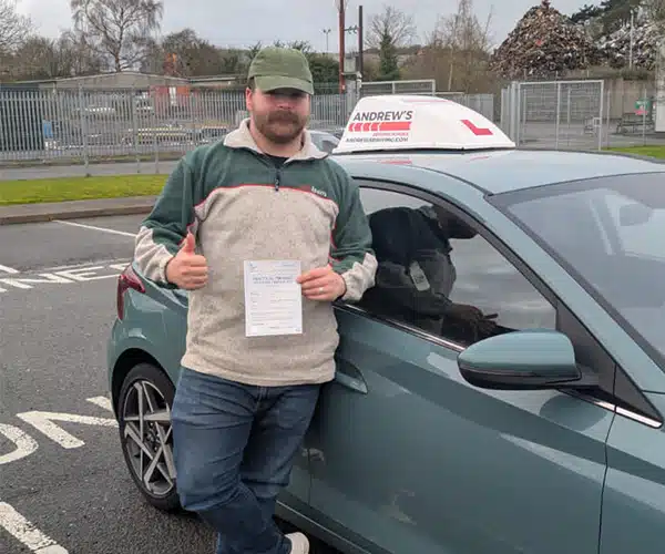 Dill from Colwyn Bay holding his pass certificate in Bangor Driving Test Centre Car Park
