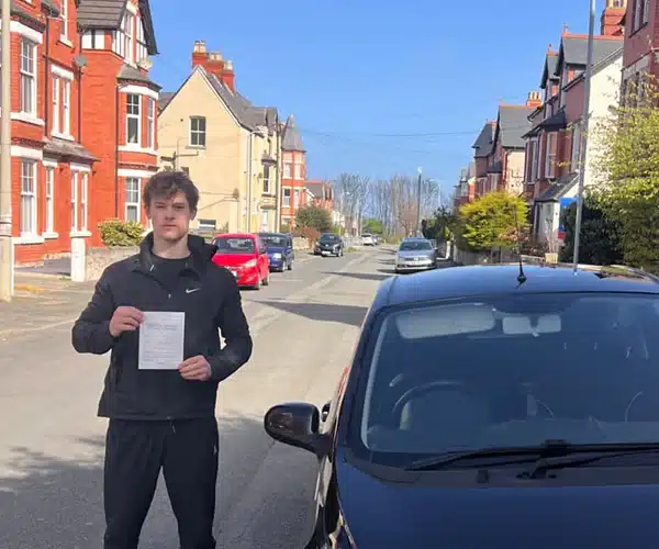 Fred holding his practical driving test pass certicar in Colwyn Bay after passing his test in Rhyl.