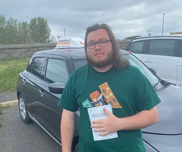 Jordan from Old Colwyn holding pass certificate after first-time driving test success in Rhyl