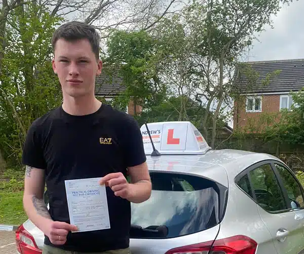 Lewis holding his driving test pass certificate atam Driving Test Centre next to Karl’s learner car