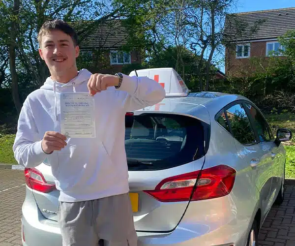"Michael holding his driving test pass certificate ham standing with instructor Karl Whitefoot's car"