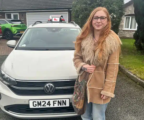 Mione standing in front of a learner car after passing her driving test in Rhyl