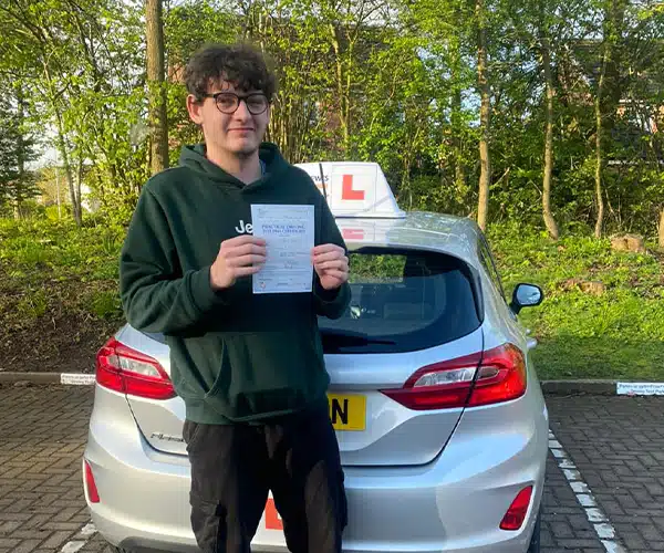 "Rhys holding his driving test pass certificate aftlongside instructor Karl Whitefoot's tuition car."