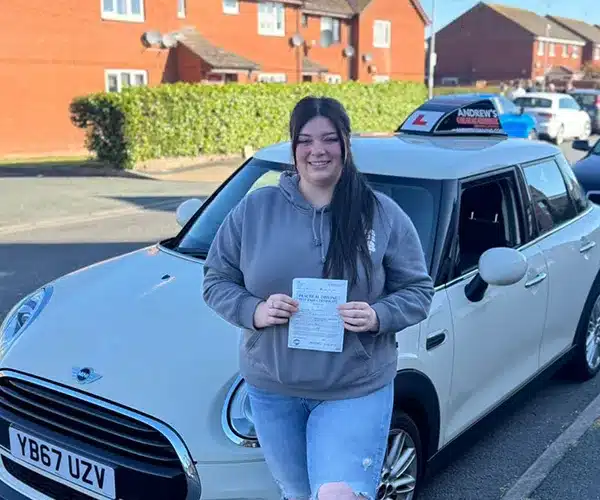 Roxanne holding her driving test pass certificate yl Driving Test Centre with Jimmy’s automatic car