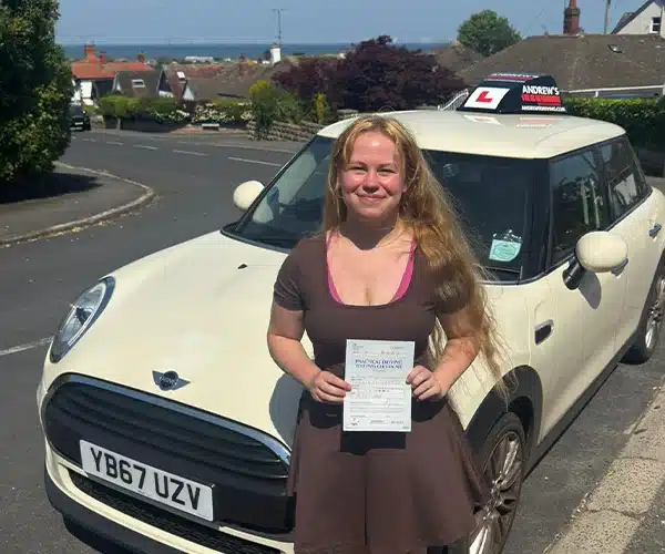 Aimee holding her driving test pass certificate beafter passing her automatic driving test in Rhyl.