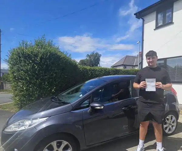 Cameron from Llandudno Junction celebrates passing his driving test in Rhyl with instructor Ben from Andrew's Driving School.