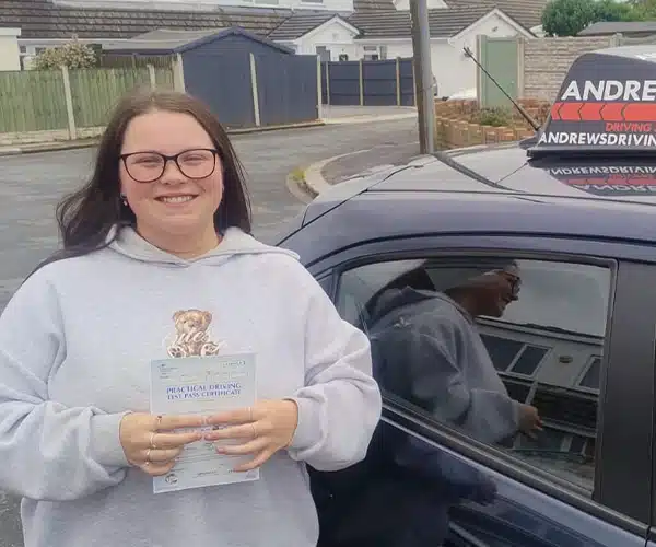 Freya celebrates passing her driving test in Rhyl with instructor Mark Bilton from Andrew's Driving School.