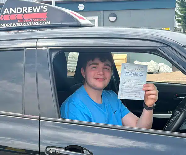 George from Anglesey celebrates passing his driving test first time in Bangor with instructor Llinos Begley from Andrew's Driving School.