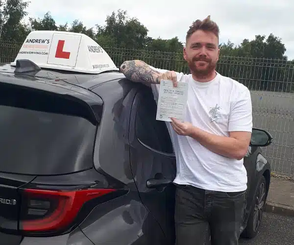 Kieran celebrates passing his automatic driving test in Bangor with zero minors and instructor Barry Evans from Andrew's Driving School.