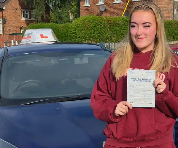 Lily holding her driving test certificate in front of Craig's tuition car in Wrexham